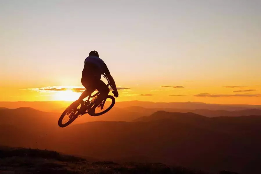 A biker jumping on a bike into the sunset.